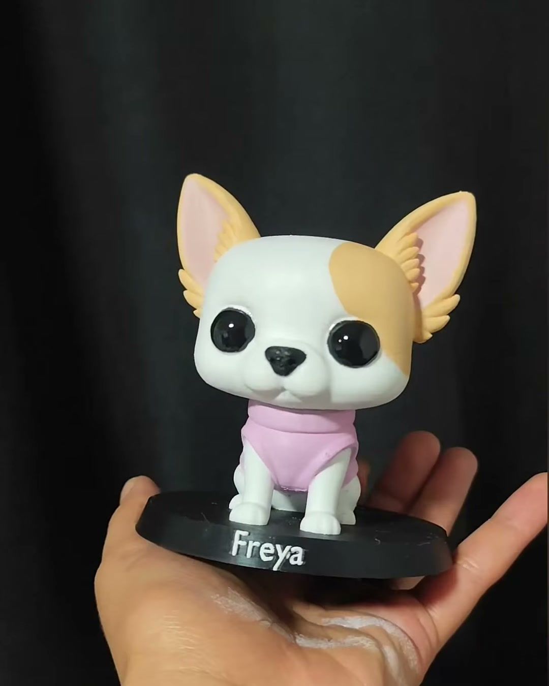 Figura de perrita chihuahua blanca y café con ropa rosada, sobre base negra con el nombre Freya.