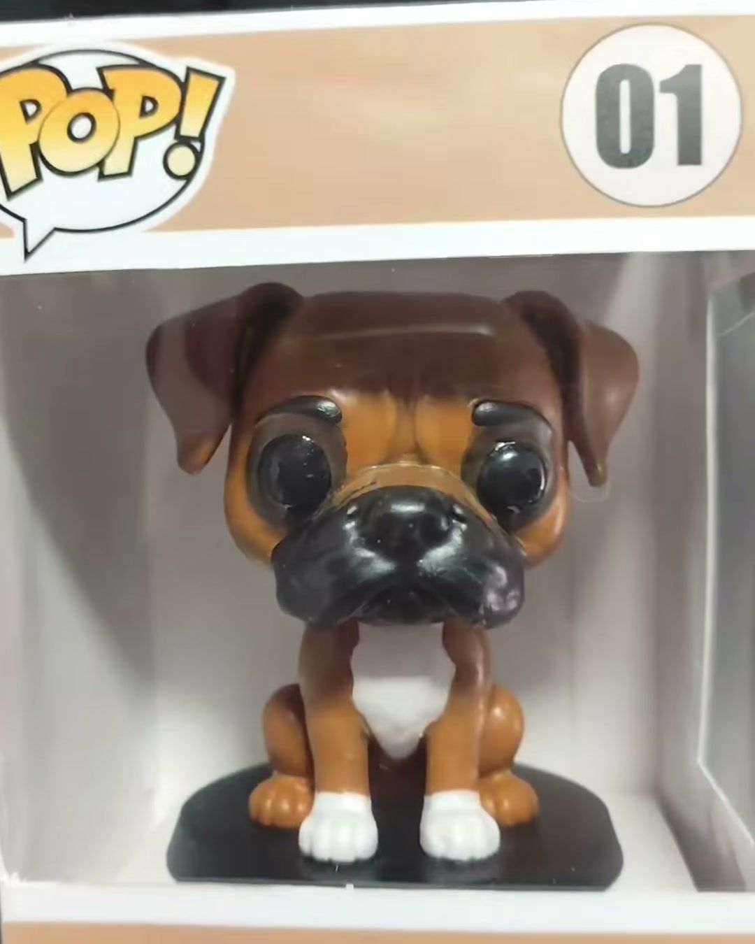 Figura de perro bóxer café y blanco dentro de una caja estilo coleccionable personalizada con el nombre Liam.