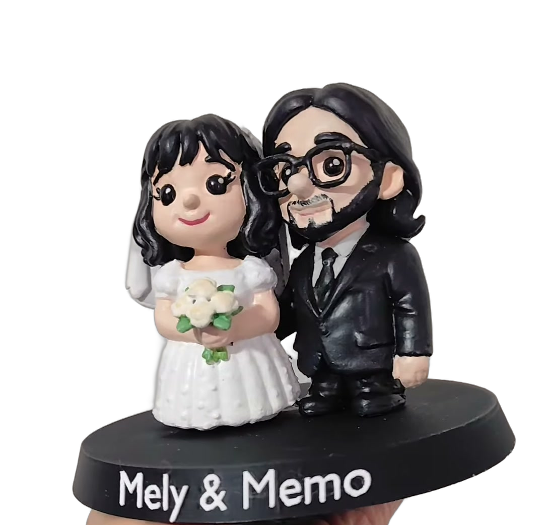 Figura de Mely y Memo, pareja de novios, sobre su base con nombres.