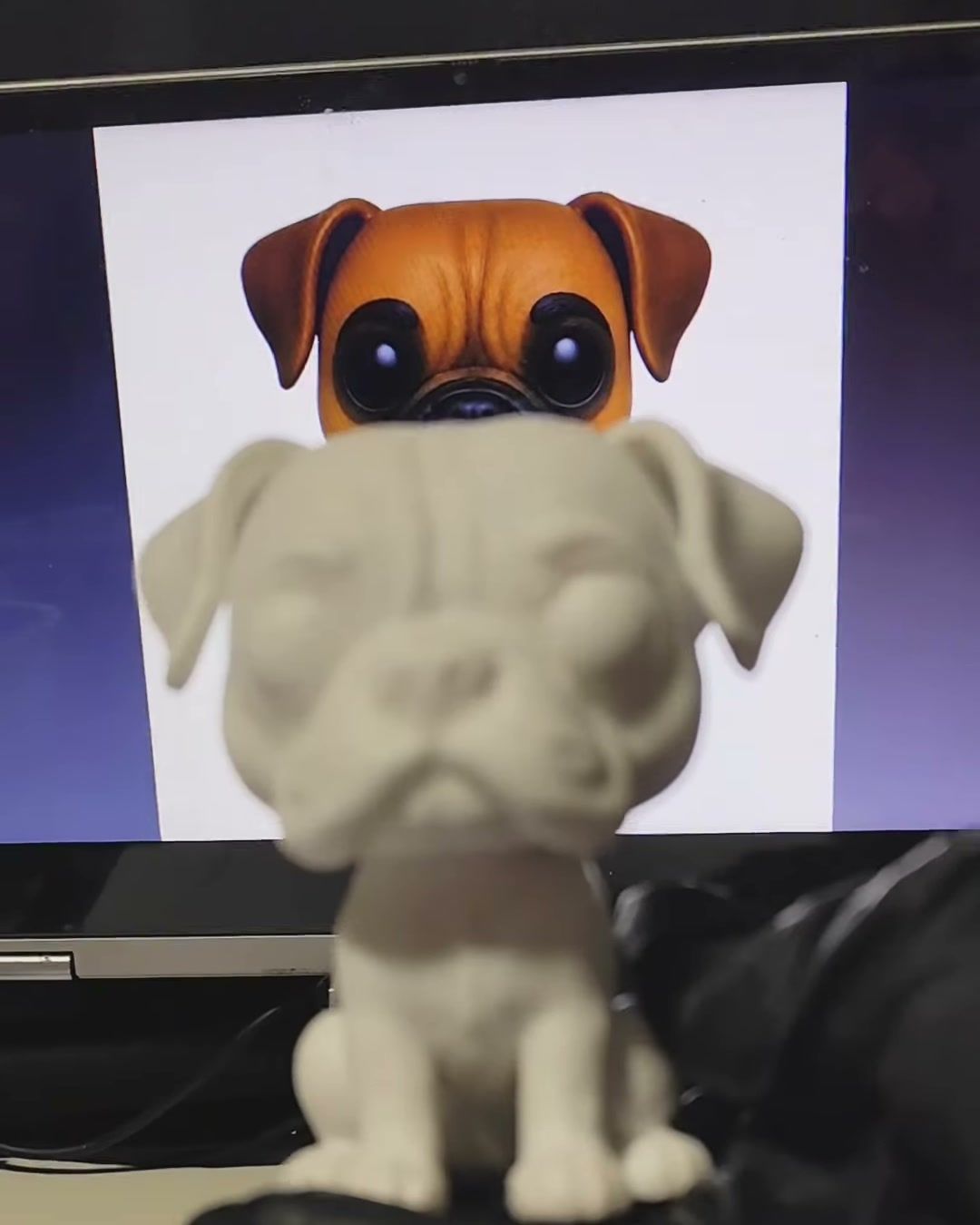Figura de un perro bóxer recién impresa, aún sin pintar, frente a la imagen de referencia.